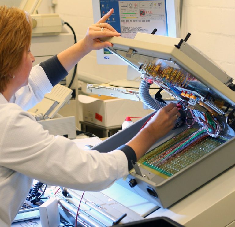 Businessfotografie in der Textilproduktion: Mitarbeiterin an einer industriellen Stickmaschine