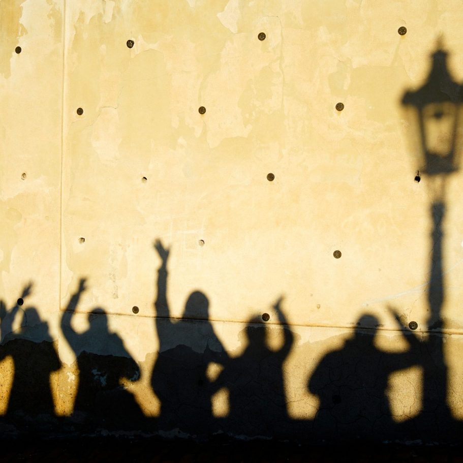 Silhouetten einer Reisegruppe vor einer sonnigen Wand mit Laterne