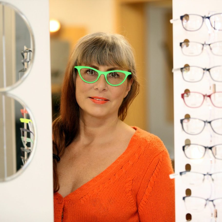 Frau mit grüner Brille bei einer persönlichen Beratung im Optikgeschäft