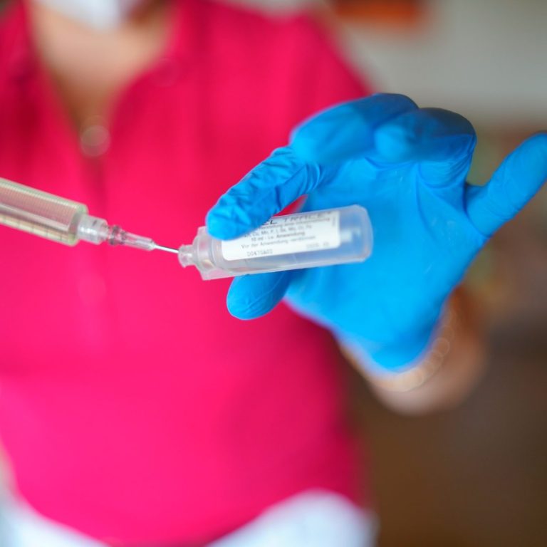 Detailaufnahme aus dem Arbeitsalltag: Laborprobe in behandschuhter Hand