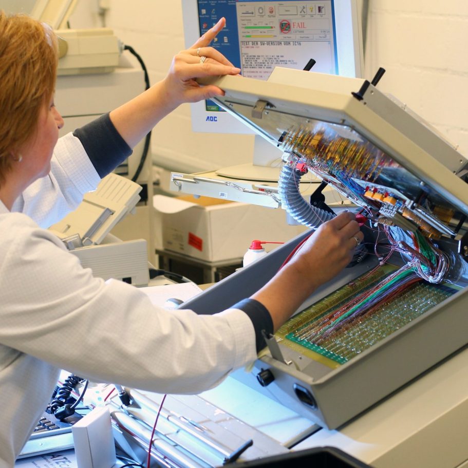 Mitarbeiterin bedient eine industrielle Stickmaschine in der Textilproduktion